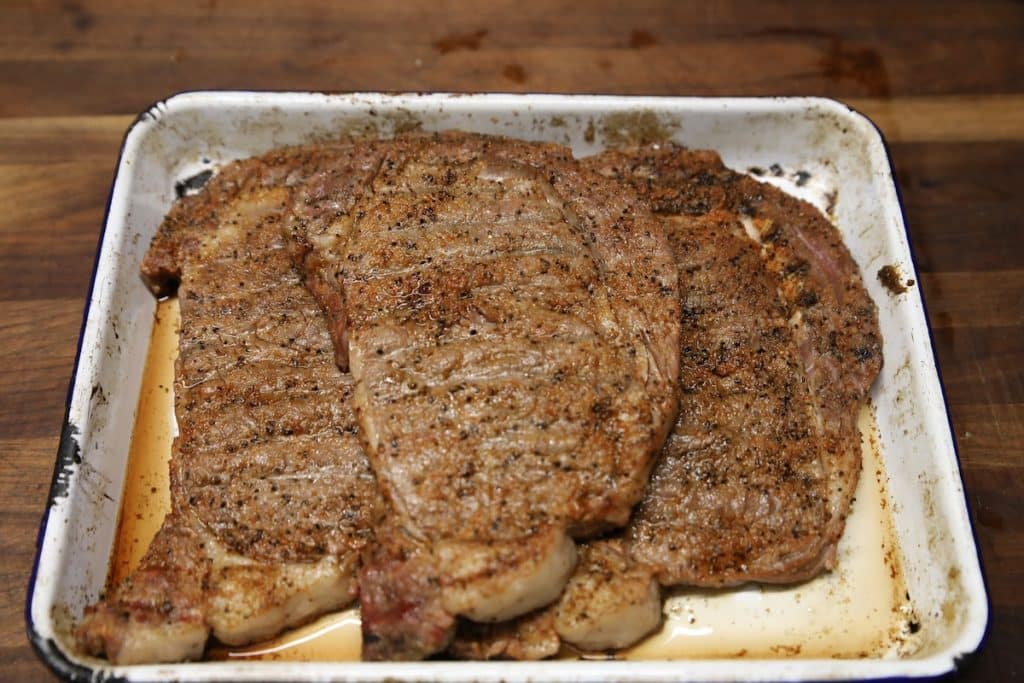 Grilled ribeye steaks on a platter.