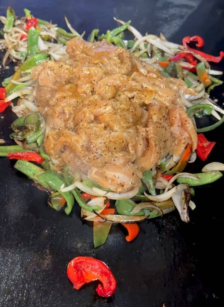 Sliced turkey, peppers and onions on blackstone for fajitas.