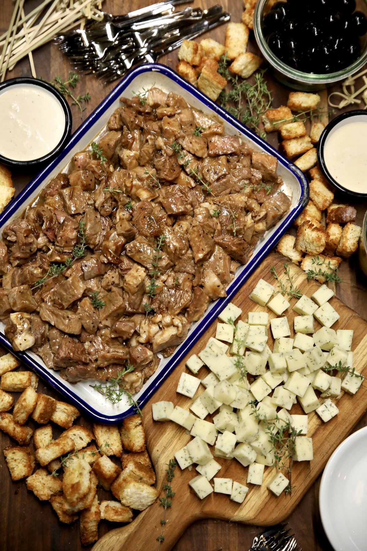 Charcuterie with steak bites, cheese, bread. Steak bites charcuterie with cheese cubes, bread cubes, olives, horseradish sauce.