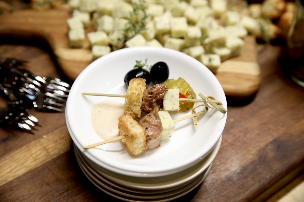 Appetizer plate with steak bites, cheese, olives pickles.