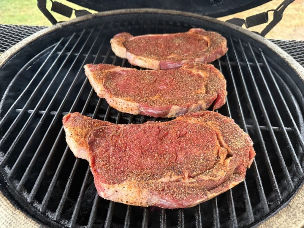 3 ribeye steaks on a grill.