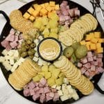 Ham and cheese charcuterie board with honey mustard, pineapple and crackers.