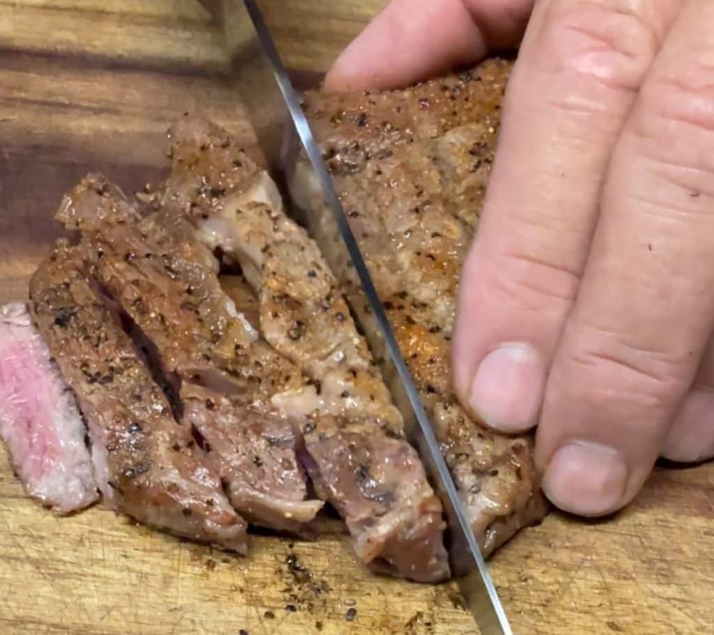 Slicing steaks on a cutting board.