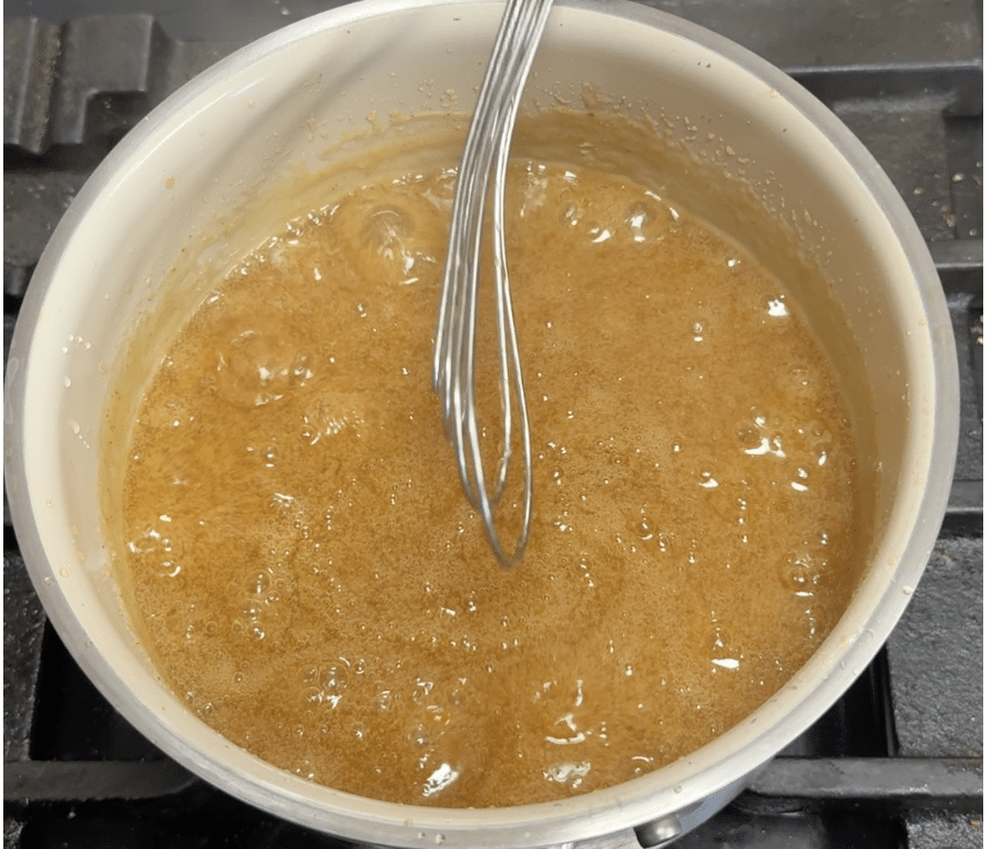 Pan of orange glaze with whisk.