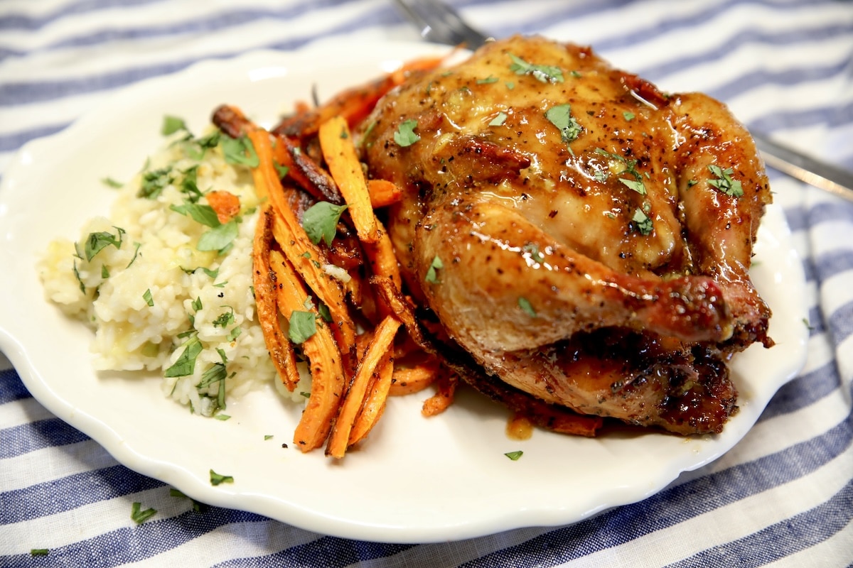 Cornish hens with orange glaze. Cornish hen with orange glaze on a plate with carrots and rice.