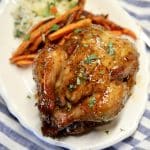 Orange glazed cornish hen on a plate with carrots.