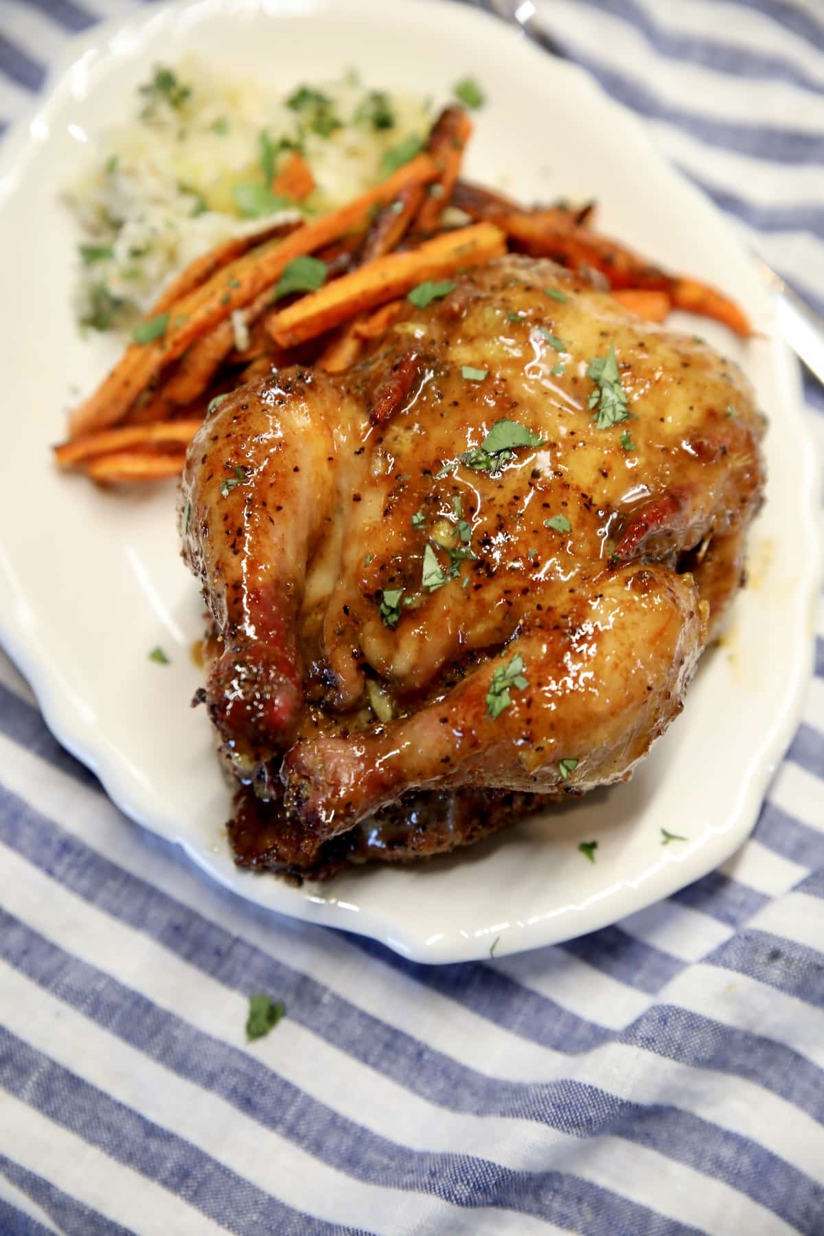 Grilled Cornish hens grilling recipe. Grilled orange glazed Cornish hen on a plate with carrots and rice.