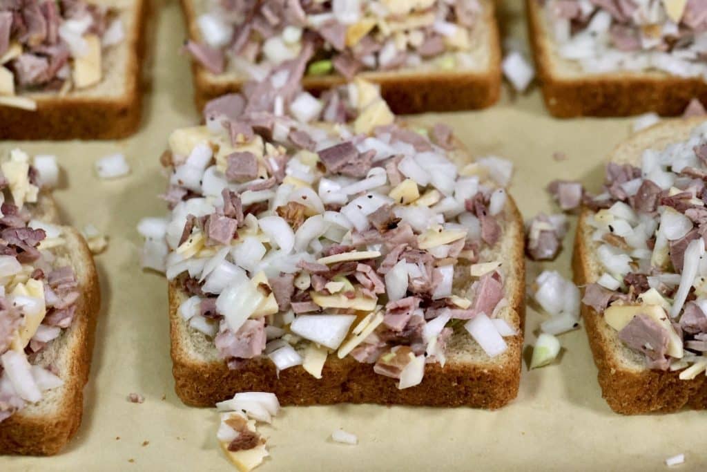 Meat, cheese and onion on slices of bread.