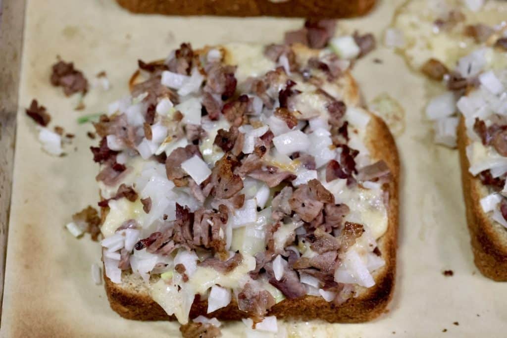 Roast beef, cheese and onion on a toasted slice of bread.