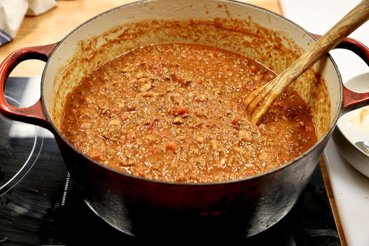 Pot of ground beef and bean chili with wood spopon.