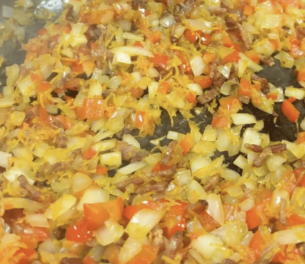 Skillet of onions, bell peppers, carrots for chili.