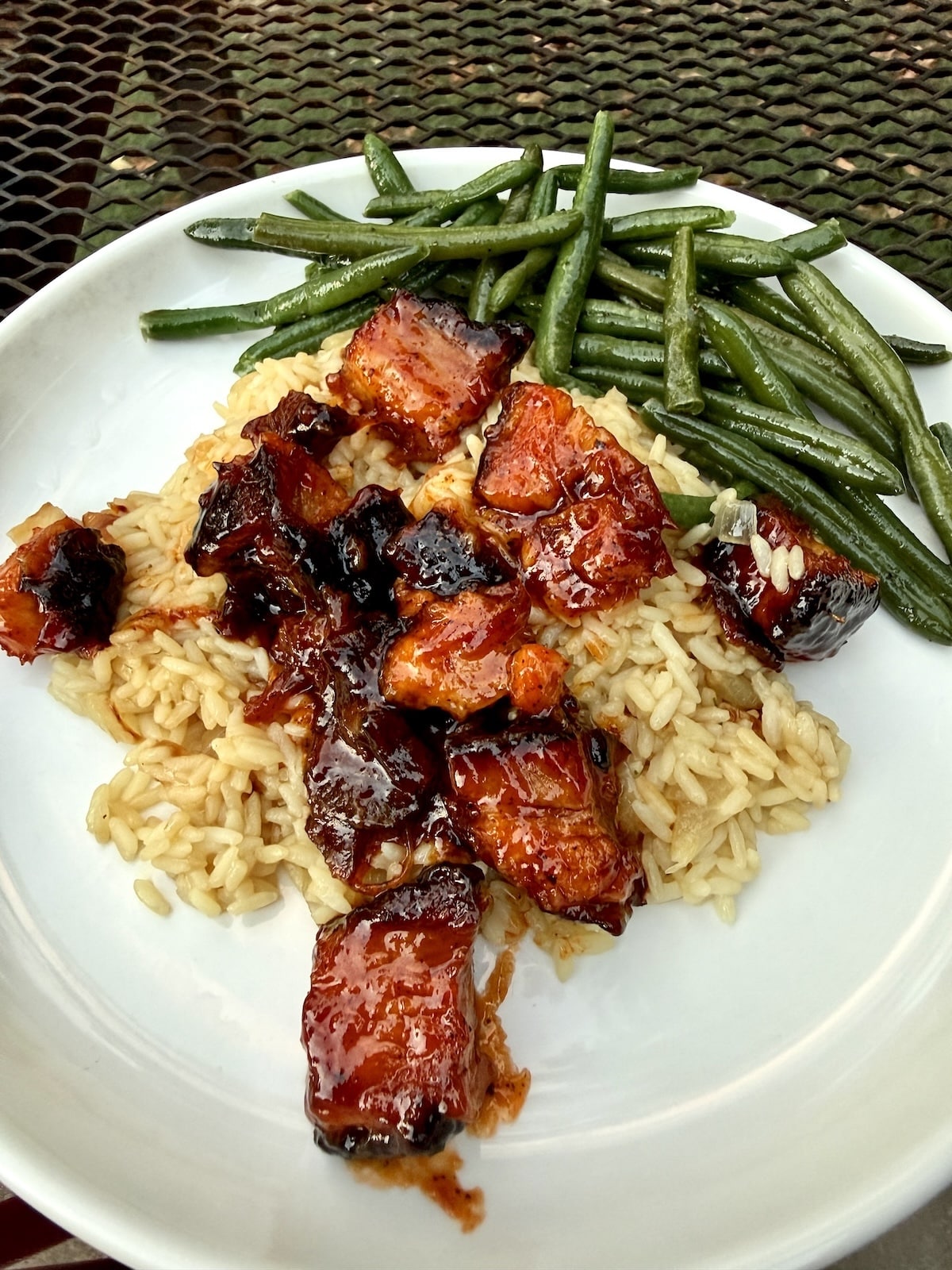 Plate of burnt ends with rice and green beans.